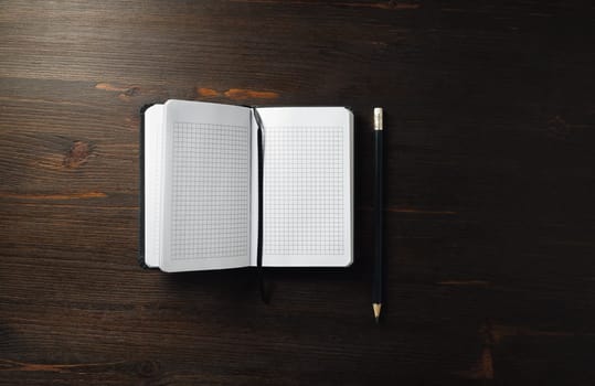 Photo of blank notebook and pencil on wood table background. Flat lay.