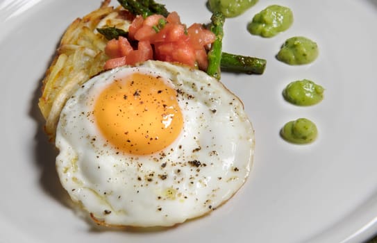 Fried egg with hashbrowns, asparagus, tomatoes and avocado sauce.