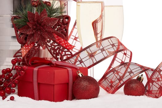 Still life with champagne bottle standing in a bucket with ice, two full champagne flutes, gift box and Christmas ornaments. Christmas and New Year background. Greeting card