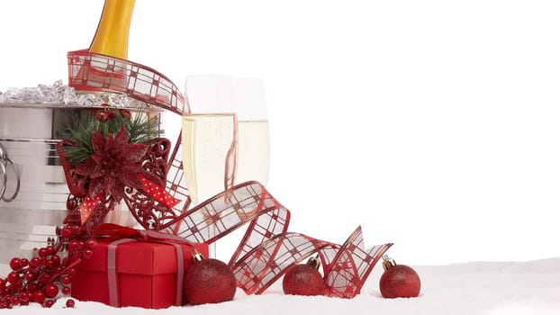 Still life with champagne bottle standing in a bucket with ice, two full champagne flutes, gift box and Christmas ornaments. Christmas and New Year background with copy space. Greeting card