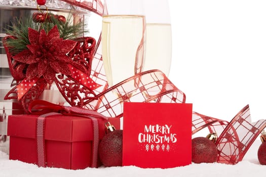 Still life with champagne bottle standing in a bucket with ice, two full champagne flutes, gift box and Christmas ornaments. Christmas and New Year background with copy space Greeting card