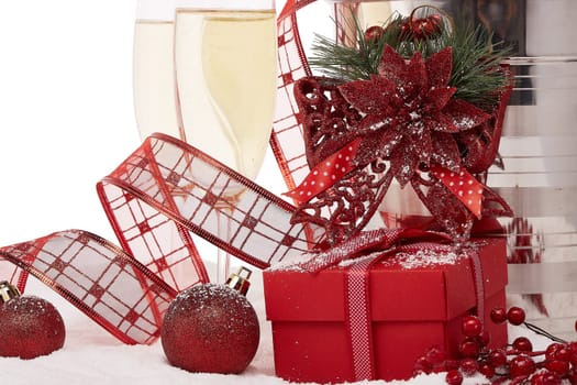 Still life with champagne bottle standing in a bucket with ice, two full champagne flutes, gift box and Christmas ornaments. Christmas and New Year background. Greeting card