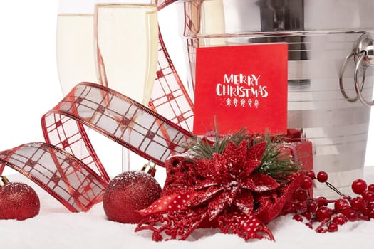 Still life with champagne bottle standing in a bucket with ice, two full champagne flutes, gift box and Christmas ornaments. Christmas and New Year background. Greeting card