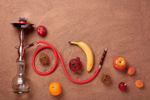 Hookah (shisha), fruit and christmas ornaments on sand background. Top view. New Year and Christmas. Winter vacation in warm countries, beach holiday