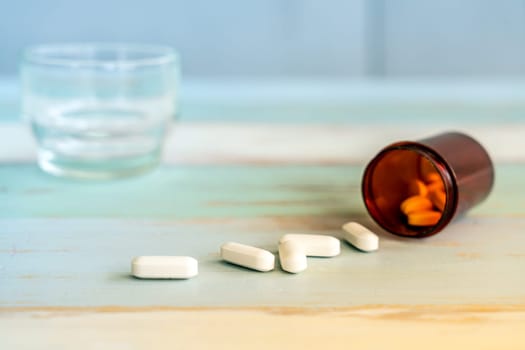 Pills medicine spilling out of pill bottle on vintage wooden background