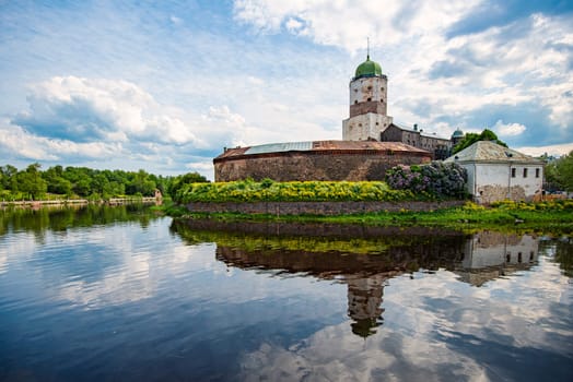 Architecture of old town Vyborg, Russia, Europe. Saint Olaf tower and Vyborg castle on summer day. Lake in foreground and sky in background