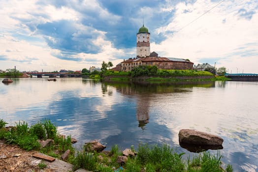 Architecture of old town Vyborg, Russia, Europe. Saint Olaf tower and Vyborg castle on summer day. Lake in foreground and sky in background