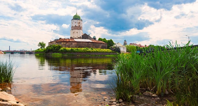 Architecture of old town Vyborg, Russia, Europe. Saint Olaf tower and Vyborg castle on summer day. Lake in foreground and sky in background