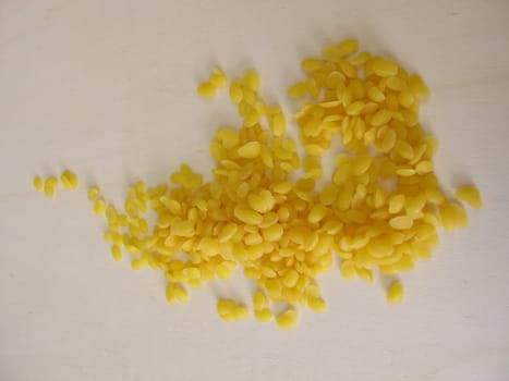 Pure beeswax pastilles for natural cosmetics, candles or beeswraps on wooden board