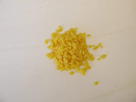 Pure beeswax pastilles for natural cosmetics, candles or beeswraps on wooden board