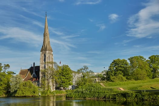COPENHAGEN, DENMARK - MAY 25, 2017: St. Alban's Church, locally often referred to simply as the English Church, is an Anglican church in Copenhagen, Denmark. The steeple reflects on the water.
