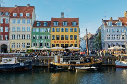 COPENHAGEN, DENMARK - MAY 25, 2017: Colourful facades and restaurants on Nyhavn embankment and old ships along the Nyhavn Canal in Copenhagen, Denmark