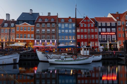 COPENHAGEN, DENMARK - MAY 25, 2017: Colourful facades and restaurants on Nyhavn embankment and old ships along the Nyhavn Canal in Copenhagen, Denmark