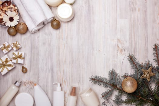 Spa still life with cosmetic creams, towel and Christmas ornaments on light wooden background. Top view with copy space. New Year and Christmas Healthy lifestyle, body care, Spa treatment