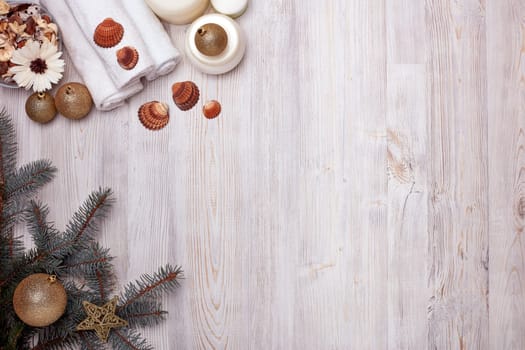 Spa still life with cosmetic creams, towel and Christmas ornaments on light wooden background. Top view with copy space. New Year and Christmas Healthy lifestyle, body care, Spa treatment