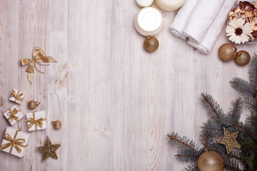Spa still life with cosmetic creams, towel and Christmas ornaments on light wooden background. Top view with copy space. New Year and Christmas Healthy lifestyle, body care, Spa treatment