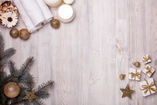 Spa still life with cosmetic creams, towel and Christmas ornaments on light wooden background. Top view with copy space. New Year and Christmas Healthy lifestyle, body care, Spa treatment