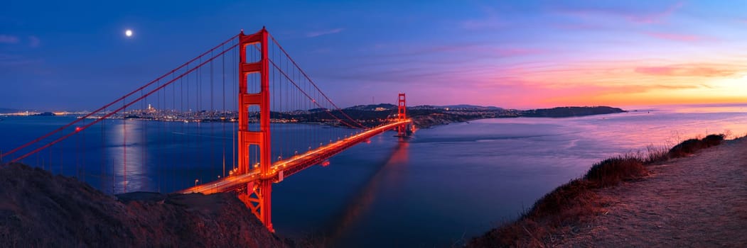 Golden Gate Bridge in San Francisco under full moon in sunset sky panorama