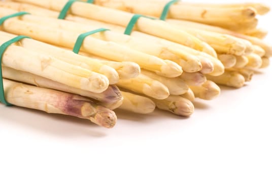 bundle of organic asparagus held together with green rubber bands isolated on white background