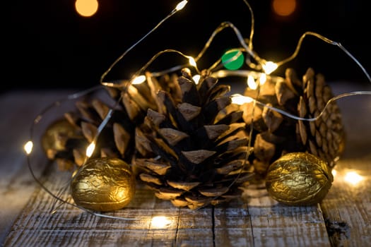 Composition of cones and painted walnuts with a garland of lpmpots and bokeh in the background
