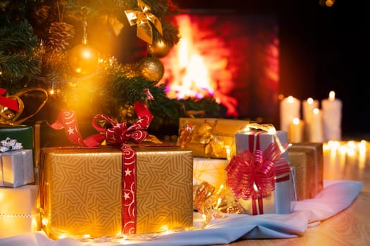Stack of packed gift boxes under Christmas tree against burning fireplace. Lots of Christmas gifts under the tree. Candles on wooden floor. Focus on golden box!