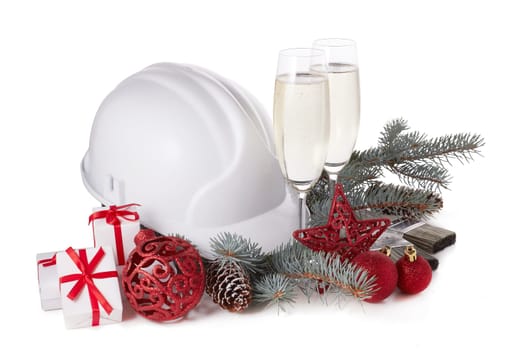 Construction hard hat, fir tree branches, two glasses with champagne, gift boxes and Christmas ornament isolated on a white background. New Year and Christmas construction background