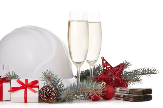 Construction hard hat, fir tree branches, two glasses with champagne, gift boxes and Christmas ornament isolated on a white background. New Year and Christmas construction background