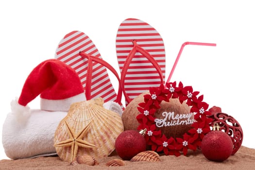 Still life with beach accessories (flip flops, towel, seashells, sand, coconut) and christmas ornaments on white background. Christmas. Winter vacation in warm countries, beach holiday