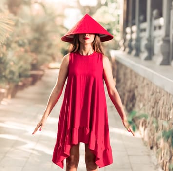 Fashion portrait of a beautiful woman in red conical hat outdoor