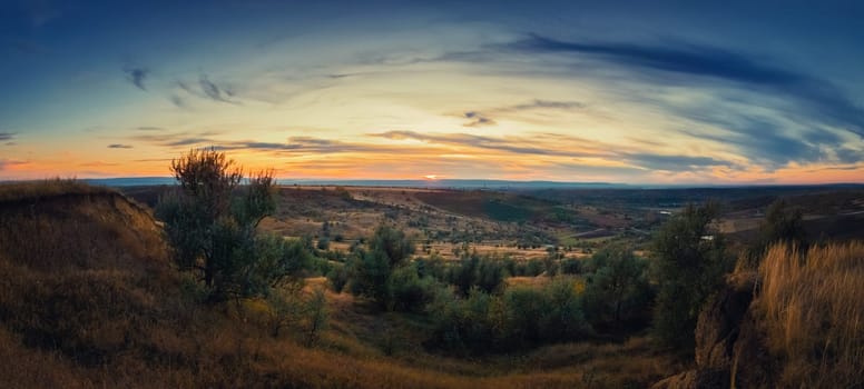 Soft autumn sunset panorama over countryside hills and valley. Beautiful rural landscape, nature scene.