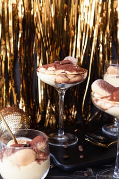 Festive tiramisu dessert in glasses with golden decorations for the holidays