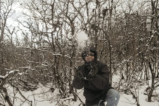 Smiling happy joyful Portrait of a Man wearing a black pullover jacket enjoying first snow playing and throwing snowball in air. Enjoy Snowing day view in winter. Rural village Jammu and Kashmir India
