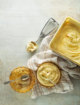 Vanilla ice cream scooped from container in to bowl with a silver utensil