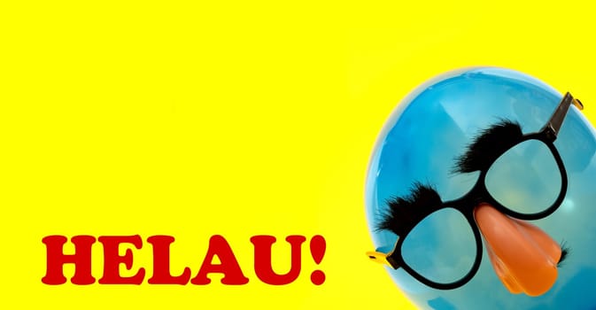 Helau german greeting for carnival - with blue Ballon with funny mask on yellow background
