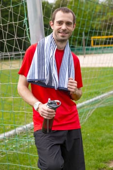 Young sportsman with towel and bottle of water