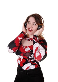 A beautiful young woman wearing a headset and signing along with.the music, with both hands on her head, isolated for white background.