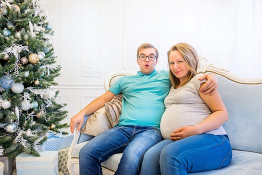 Family portrait near christmas tree. Pregnant woman.