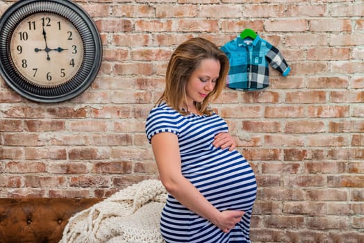 Beautiful pregnant woman sitting near brick wall