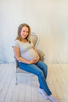Beautiful pregnant woman sitting on the armchair