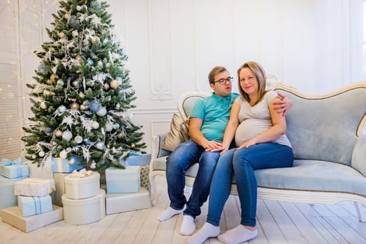 Family portrait near christmas tree. Pregnant woman.