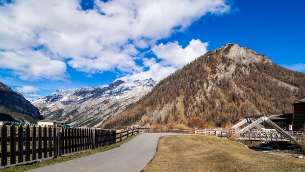 Beautiful mountain valley with stream, trees, footpath and wooden bridge, Livigno is a small town and ski centre for Italian Alps, Italy