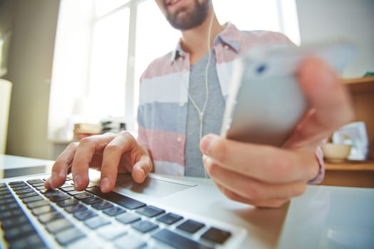 Young man using multi-media gadgets in office