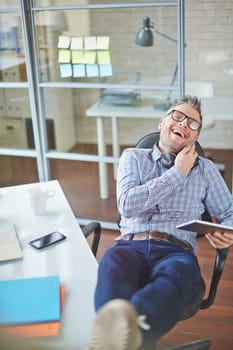 Happy young man speaking on cellphone by workplace