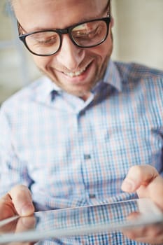 Smiling businessman in eyeglasses browsing in touchpad