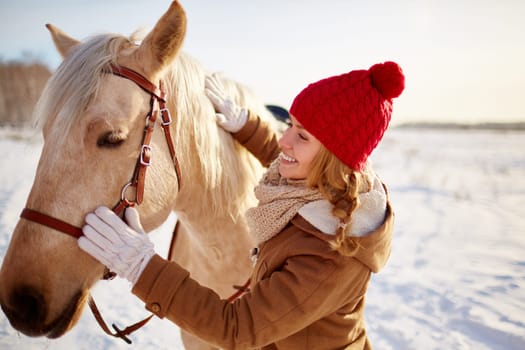 Young female in winterwear looking at horse