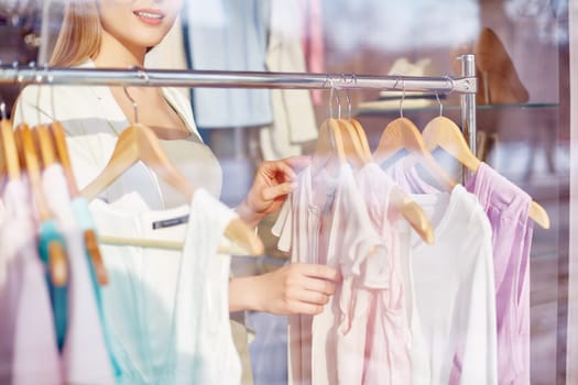 Beautiful young woman choosing new blouse for summer