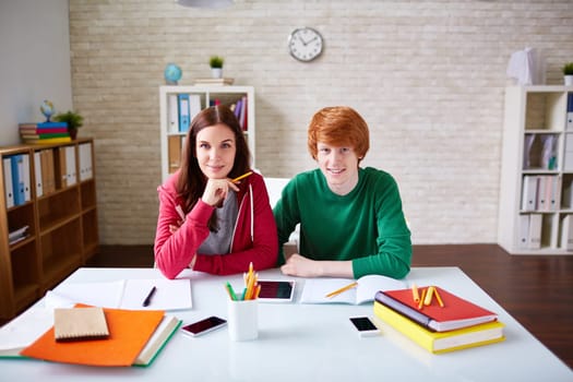 Cute teenage friends sitting in library