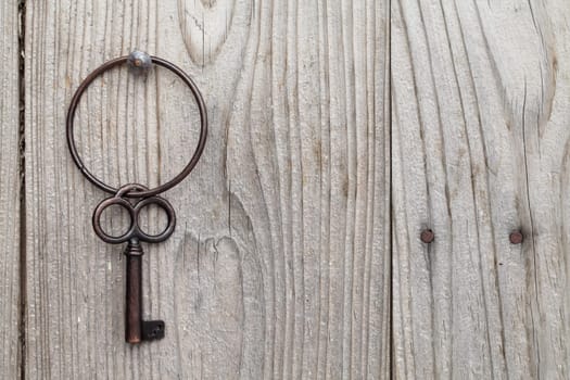 Old rusty key hanging on wooden wall