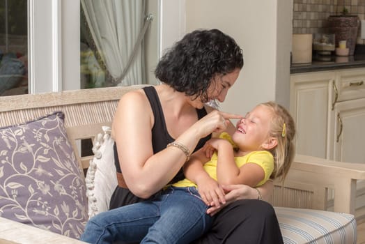 A mother and her young daughter having fun and playing on the patio.