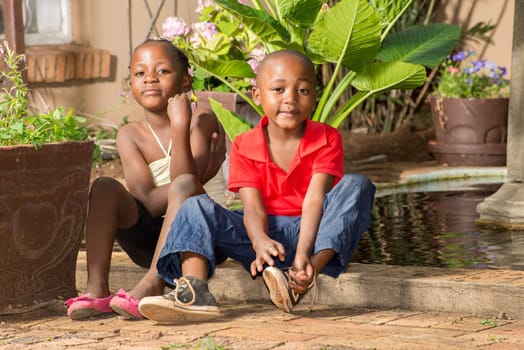 Boy ties his shoe laces after he and his twin sister played at the pond by their house.